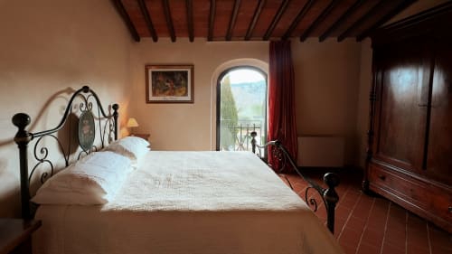 Camera da letto dell'appartamento Leonardo a Borgo di Erboli a Cavriglia, Italia - letto in ferro battuto e finestra ad arco con vista