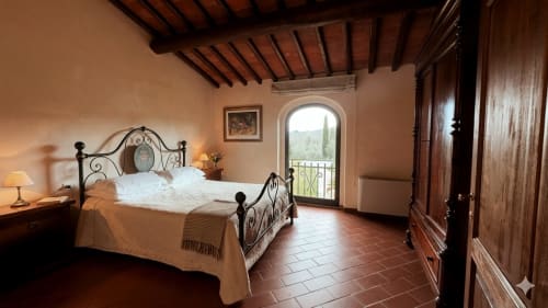 Camera Leonardo a Borgo di Erboli a Cavriglia con letto in ferro battuto, pavimento in cotto e porta-balcone ad arco