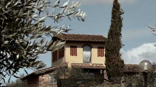 Villa toscana a Borgo di Erboli con muri gialli, cipresso e rami d'ulivo che incorniciano la vista