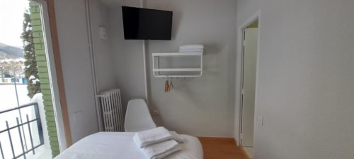 Habitación individual en Hotel del Trueno en Ezcaray con cama, televisor, vistas por la ventana y toallas en el perchero