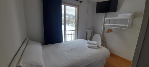 Habitación individual en Hotel del Trueno de Ezcaray con cama, TV, balcón con vistas a la montaña y comodidades modernas
