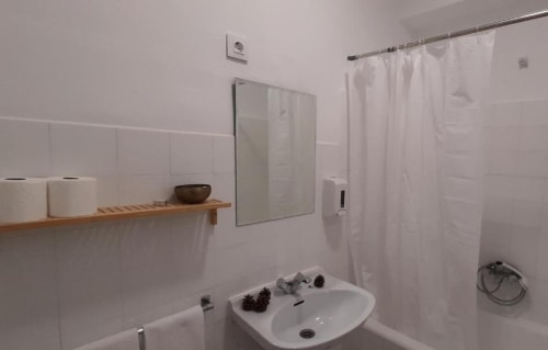 Clean bathroom at Hotel del Trueno in Ezcaray with white tiles, sink, mirror, and shower curtain