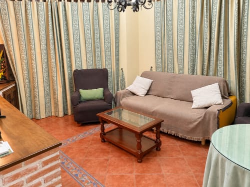 Sala de estar del apartamento La Posada en Oropesa con sofá beige, sillón y cortinas a rayas