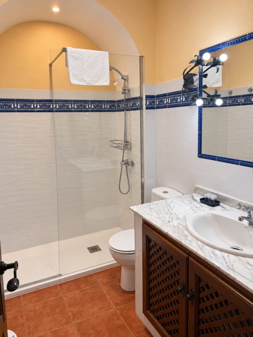 Baño moderno en Apartamentos La Posada, Oropesa con ducha abierta, tocador de mármol y detalles decorativos en azul