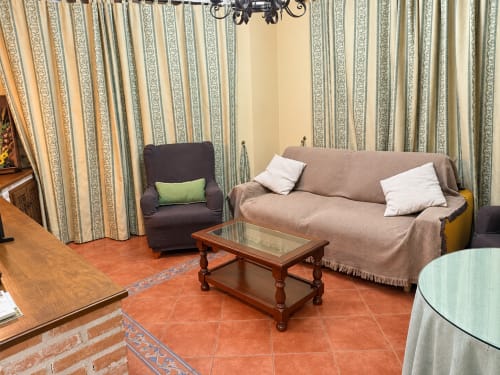 Sala de estar en apartamento de 1 dormitorio en La Posada, Oropesa Toledo con sofá beige, sillón, mesa de café de madera y