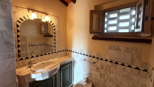 Bagno dell'appartamento Galileo a Borgo di Erboli, Cavriglia - vanità con specchio, toilette e dettagli in piastrelle bianche e nere
