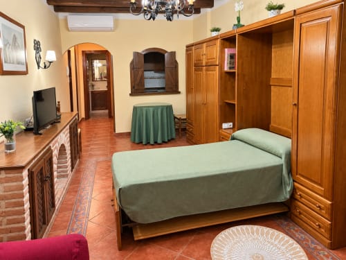 Estudio en La Posada, Oropesa (Toledo) con muebles de madera, cama verde y suelos de barro cocido