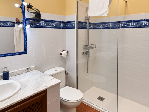 Baño moderno en apartamento La Posada, Oropesa Toledo con tocador de mármol, ducha de cristal y detalles en azulejos azules