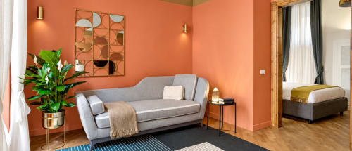 Luxury Rome apartment living room with coral walls, gray sofa, modern decor, and bedroom view at Trevi House