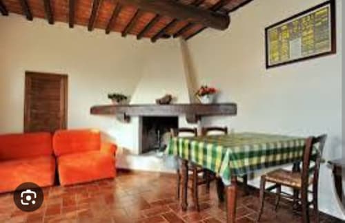 L'appartamento Tommaso nel Borgo di Erboli a Cavriglia presenta travi rustiche, divano rosso, tavolo da pranzo con stoffa verde e
