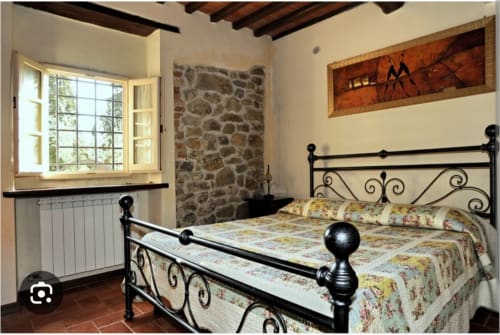 Camera da letto dell'appartamento Tommaso a Borgo di Erboli a Cavriglia, Italia, con letto in ferro battuto e muro in pietra rustica