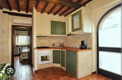 Cucina dell'appartamento Tommaso a Borgo di Erboli, Cavriglia con mobili verdi, pavimenti in cotto e travi in legno