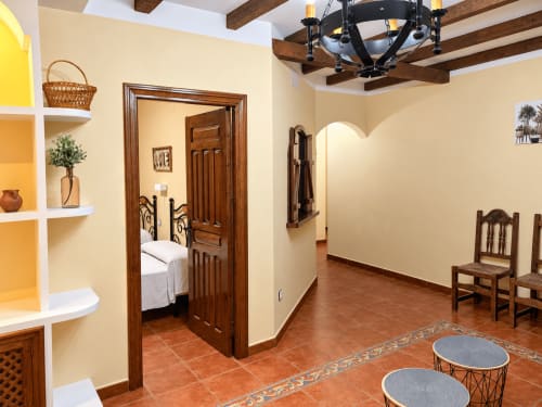 Amplio salón con vigas de madera, suelos de barro cocido y amueblamiento rústico en La Posada, Oropesa Toledo