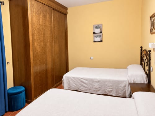 Acogedora habitación en Apartamentos Turísticos La Posada de Oropesa con camas gemelas, armario de madera y paredes amarillas