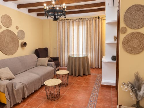 Acogedora sala de estar de apartamento de 1 dormitorio en La Posada, Oropesa, Toledo con vigas de madera, paredes amarillas y terracota