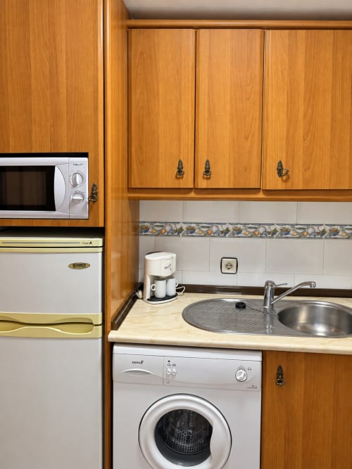 Cocina compacta en Apartamentos Turísticos La Posada, Oropesa Toledo con muebles de madera, microondas, horno y lavadora