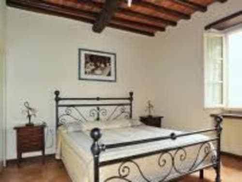 Lapo apartment bedroom at Borgo di Erboli in Cavriglia with iron bed, wooden beams, and rustic decor