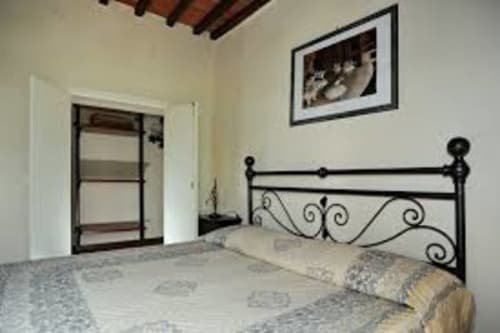 Camera da letto dell'appartamento Lapo a Borgo di Erboli con letto in ferro battuto, armadio e pareti bianche