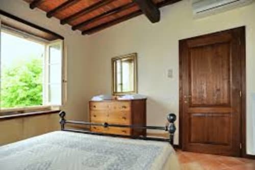Camera da letto dell'appartamento Lapo a Borgo di Erboli, Cavriglia, con travi in legno, letto in ferro battuto e vista sulla campagna