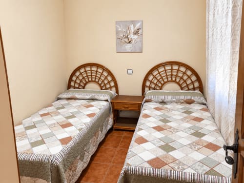Habitación doble con cabeceros de ratán y colchas estampadas en Apartamentos Turísticos La Posada, Oropesa, Toledo