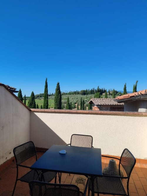 Terrazza toscana al Borgo di Erboli con tavolo da pranzo vista cipressi e uliveti