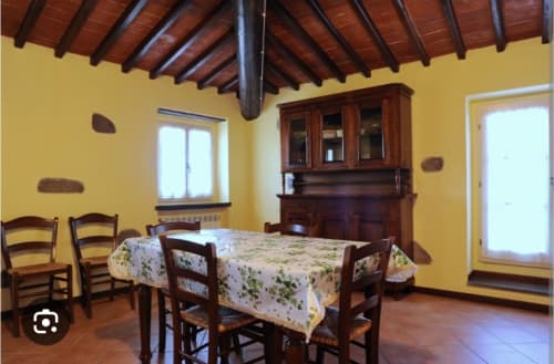 Luminosa sala da pranzo gialla con travi in legno, arredamento rustico e credenza tradizionale al Borgo di Erboli a Cavriglia