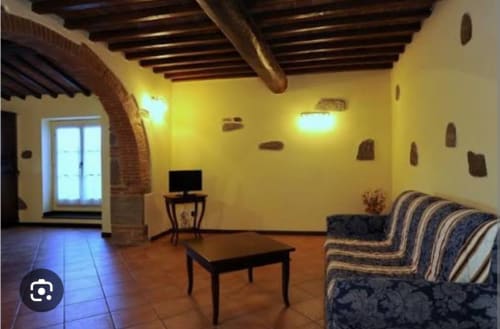 Appartamento Eleonora a Borgo di Erboli a Cavriglia con pareti gialle, travi a vista, divano rigato e pavimento in cotto
