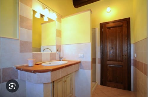Bagno dell'appartamento Eleonora a Borgo di Erboli a Cavriglia con vanity in legno, lavabo rotondo e piastrelle gialle.