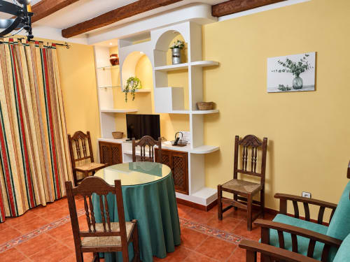 Luminoso apartamento amarillo en La Posada, Oropesa Toledo, con suelo de terracota, mesa redonda, sillas de madera y estanterías blancas