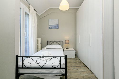 Camera moderna nella Lavanda House 701, appartamento Genova con letto in metallo nero e biancheria bianca