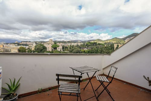 Terrazza in rooftop con sedute con vista sugli edifici storici di Genova e il paesaggio collinare