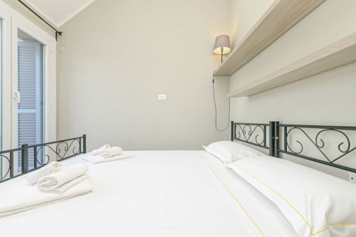 Camera moderna a Lavanda House 701 a Genova con letti gemelli, testiere in ferro battuto e servizi contemporanei.