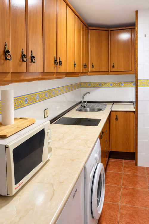 Cocina moderna en Apartamentos La Posada, Oropesa Toledo con muebles de madera, encimeras de mármol y azulejos decorativos amarillos