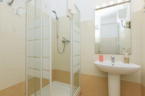 Bagno moderno con box doccia in vetro, lavabo su piedistallo e piastrelle beige nell'appartamento Lavanda House 701 a Genova