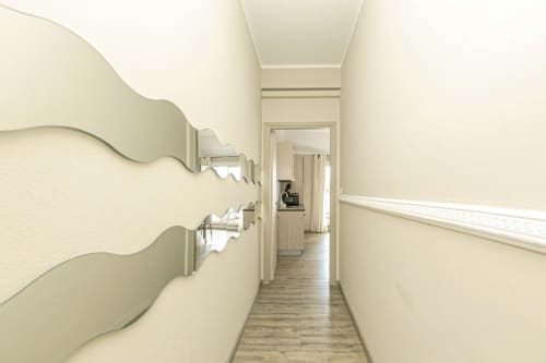 Lungo corridoio stretto dell'appartamento Lavanda House 701 a Genova con pareti color crema e pavimentazione in legno
