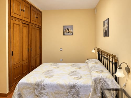 Habitación luminosa en La Posada de Oropesa, Toledo con armario de madera, ropa de cama estampada y arte en la pared