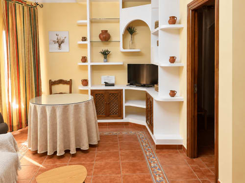 Apartamento La Posada en Oropesa con tejas de barro, estanterías blancas, TV, mesa redonda y detalles rústicos de madera