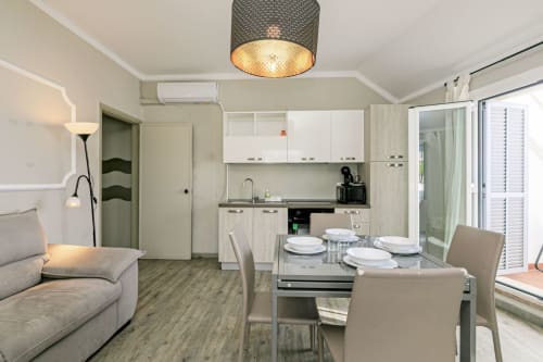 Cucina e zona pranzo moderna a Genova con cabinetry bianca, tavolo da pranzo e porte scorrevoli verso il balcone