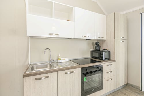 Cucina moderna nella casa Lavanda 701, appartamento a Genova con mobili bianchi, lavello in acciaio inox e forno nero