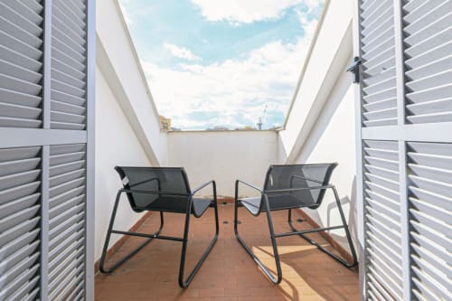 Elegante terrazza con due sedie lounge, lucernario e vista panoramica di Genova a Lavanda House 701