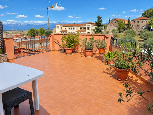 Terraza de La Posada hotel apartamento en Oropesa, Toledo con plantas en macetas, vistas al campo y montañas al fondo