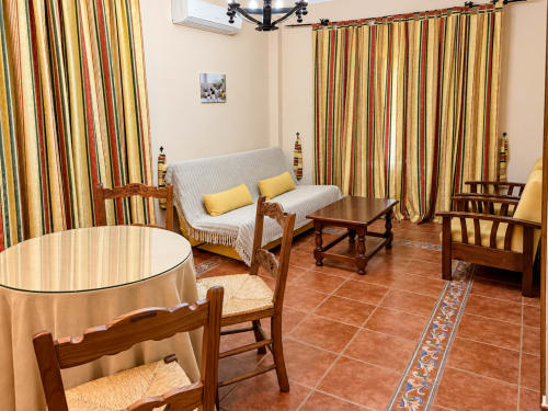 Acogedora sala de estar en La Posada, Oropesa (Toledo) con cortinas a rayas, muebles de madera y suelo de barro