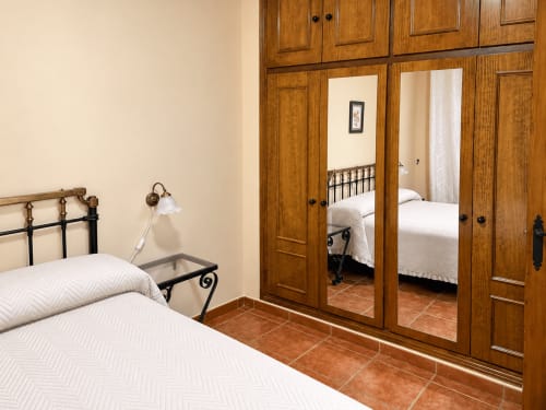 Dormitorio en Apartamentos Turísticos La Posada de Oropesa, Toledo con cama, armario con espejo y piso de barro cocido
