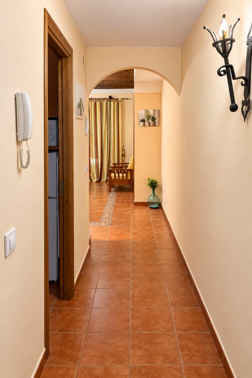 Pasillo en Apartamentos Turísticos La Posada, Oropesa Toledo, con azulejos de barro y puerta con arco