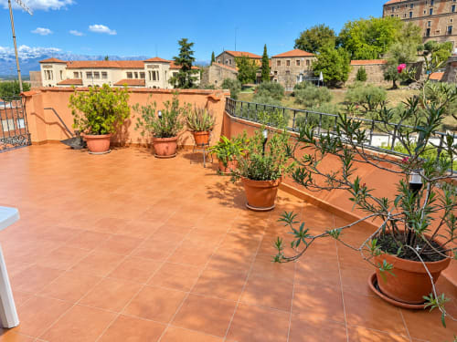 Terraza de barro cocido en La Posada de Oropesa con macetas y vistas a las montañas