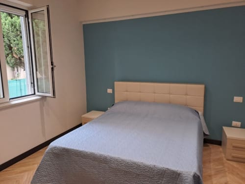 Modern bedroom at Sweet Elite House B&B in Scafati with beige headboard, blue accent wall, and garden view