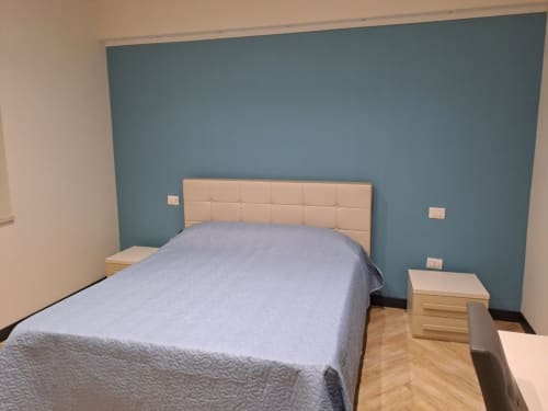 Modern bedroom at Sweet Elite House B&B in Scafati with blue accent wall, beige headboard, and wooden flooring