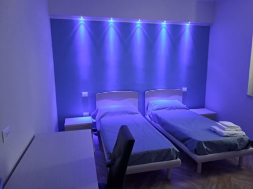 Modern bedroom at Sweet Elite House Scafati with twin beds, blue LED lighting, and contemporary design.