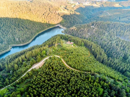 Vue aérienne de montagnes boisées avec rivière bleue sinueuse et petit bâtiment à Saint-Étienne, France