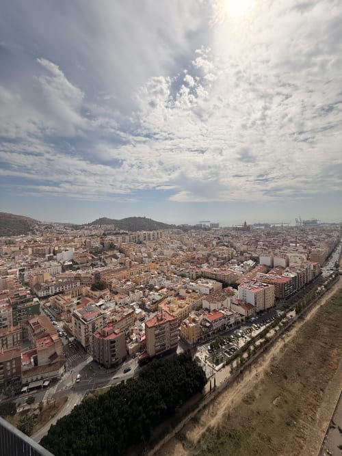 Vista aérea del paisaje urbano de Málaga con edificios residenciales densos, montañas al fondo y cielo nublado de Sinese Design
